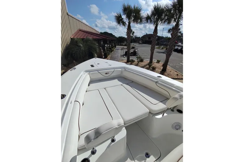 Slide: The Image of 2019 Sea Hunt Gamefish 27 boat interior with cushioned seating, parked near palm trees. - 17