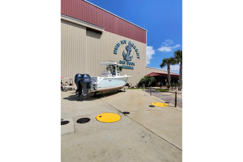 Slide: The Image of 2019 Sea Hunt Gamefish 27 boat at a marina with palm trees and blue sky. - 19