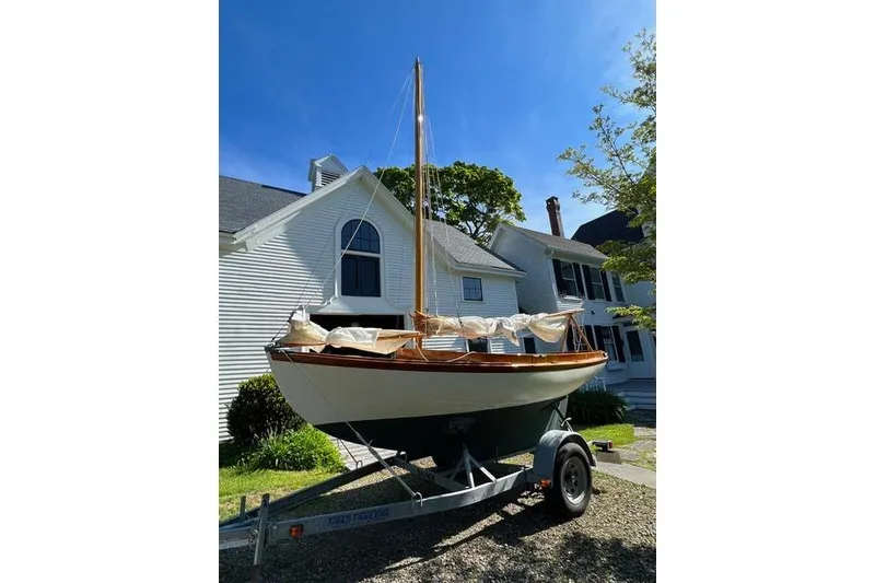 The Image of 2003 Herreshoff 12 1/2 sailboat on trailer, parked in front of a white house. - 1