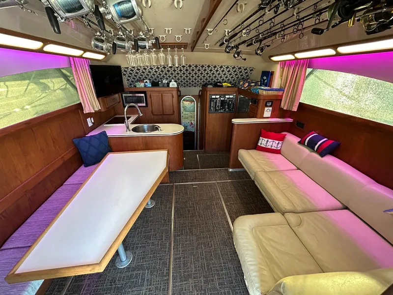 Slide: The Image of 1993 Luhrs Tournament 380 Convertible yacht interior with seating, table, and fishing rods. - 13