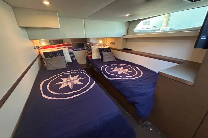Slide: The Image of Interior of 2012 Sea Ray 450 Sedan Bridge with twin beds and nautical decor. - 13