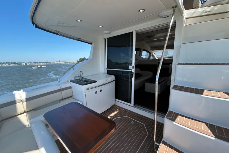 Slide: The Image of 2012 Sea Ray 450 Sedan Bridge yacht deck with seating, sink, and stairs. - 3