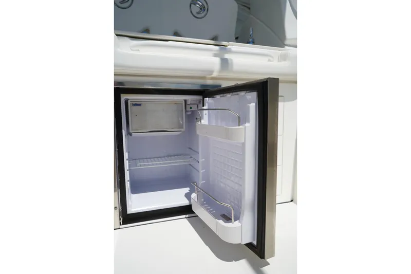 Slide: The Image of Open mini fridge on 2020 Edgewater 262CX Crossover boat, showcasing interior storage space. - 16