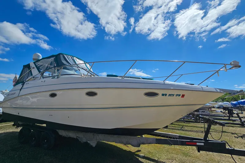 Slide: The Image of 2000 Larson Cabrio 330 boat on trailer under a bright blue sky. - 2