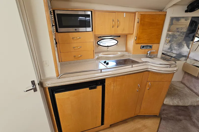 Slide: The Image of Interior view of a 2000 Larson Cabrio 330 boat kitchen with wooden cabinets and modern appliances. - 20