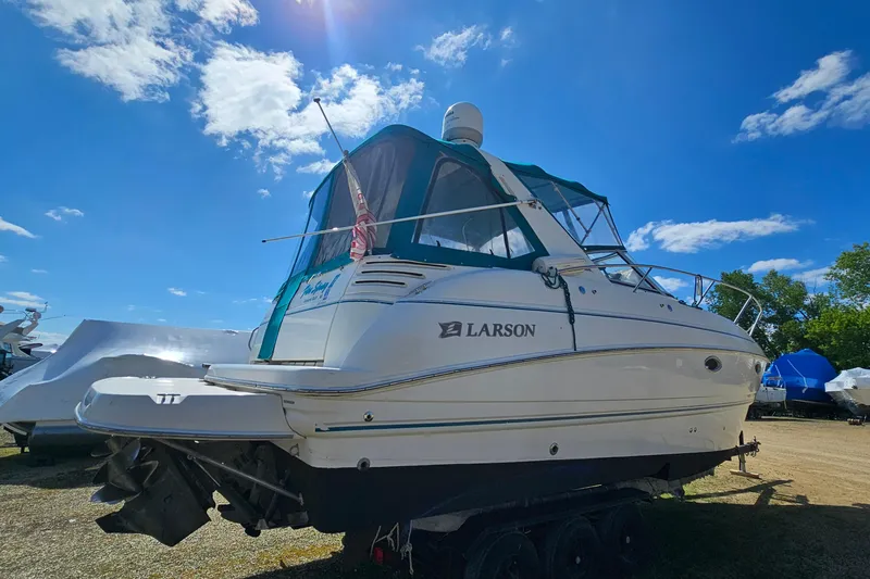 Slide: The Image of 2000 Larson Cabrio 330 boat with canopy, parked outdoors under a clear blue sky. - 3