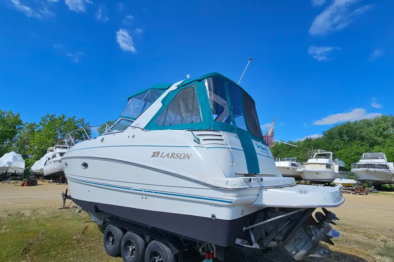 Slide: The Image of 2000 Larson Cabrio 330 boat on trailer under clear blue sky. - 4