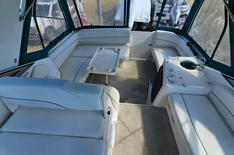 Slide: The Image of Interior of a 2000 Larson Cabrio 330 boat with white seating and a small table. - 7
