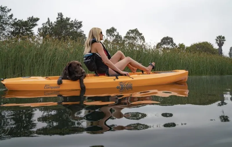 Slide: The Image of Woman and dog kayaking on a 2023 Hobie Compass in a serene lake. - 2
