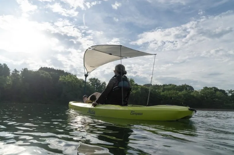 Slide: The Image of Person kayaking on a 2023 Hobie Compass with a sunshade on a calm lake. - 4