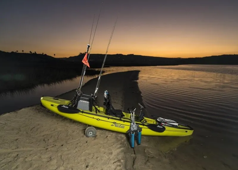 Slide: The Image of 2023 Hobie Compass kayak at sunset on a sandy shore, equipped for fishing. - 5