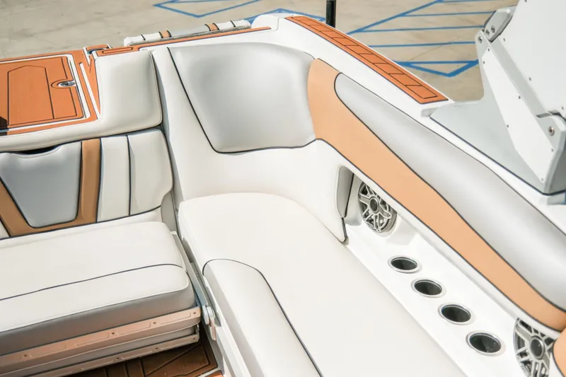 Slide: The Image of 2021 MB F24 Tomcat Alpha boat interior with white and tan seating, cup holders, and speakers. - 23