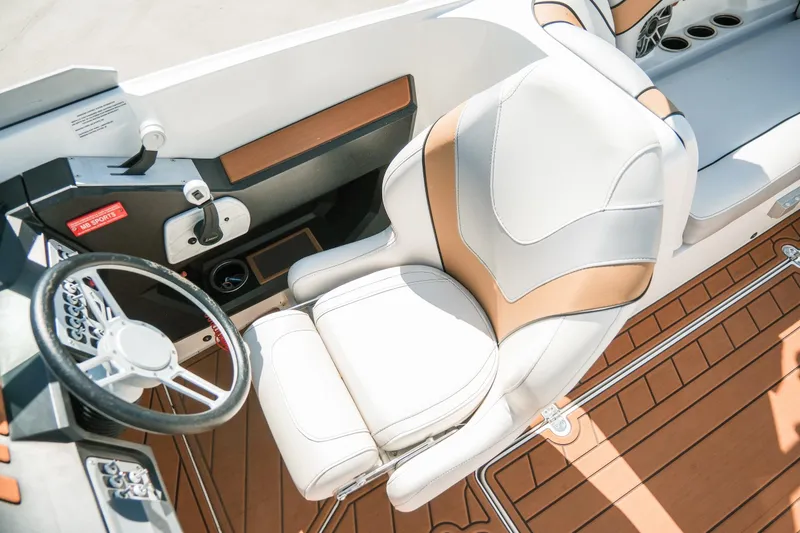 Slide: The Image of 2021 MB F24 Tomcat Alpha boat interior with white and tan seating, steering wheel, and controls. - 24