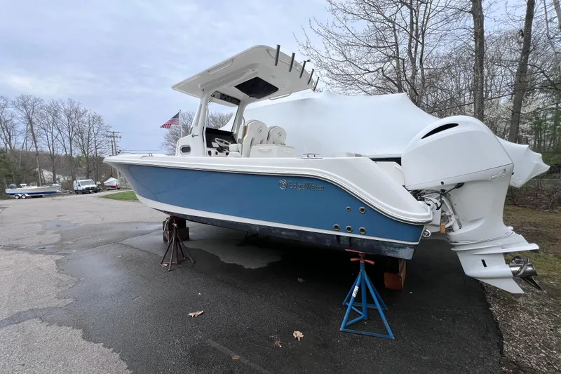 Slide: The Image of 2022 Edgewater 262CC boat on stands, blue hull, parked outdoors. - 1