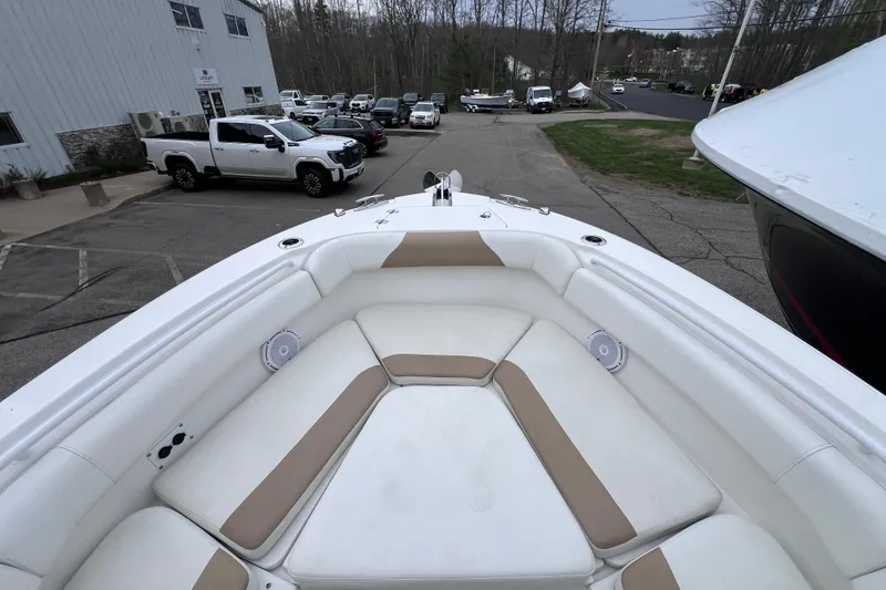 Slide: The Image of 2022 Edgewater 262CC boat with spacious seating, parked outdoors near vehicles and trees. - 12