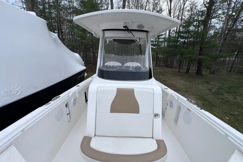 Slide: The Image of 2022 Edgewater 262CC boat with seating, helm, and canopy in wooded area. - 13