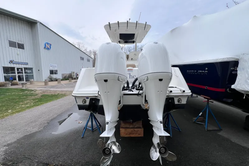 Slide: The Image of 2022 Edgewater 262CC boat with dual outboard motors, parked near a marine service building. - 2