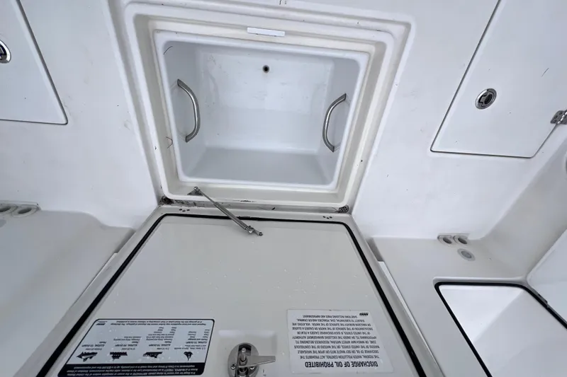 Slide: The Image of 2022 Edgewater 262CC boat storage compartment with open hatch and safety instructions. - 23