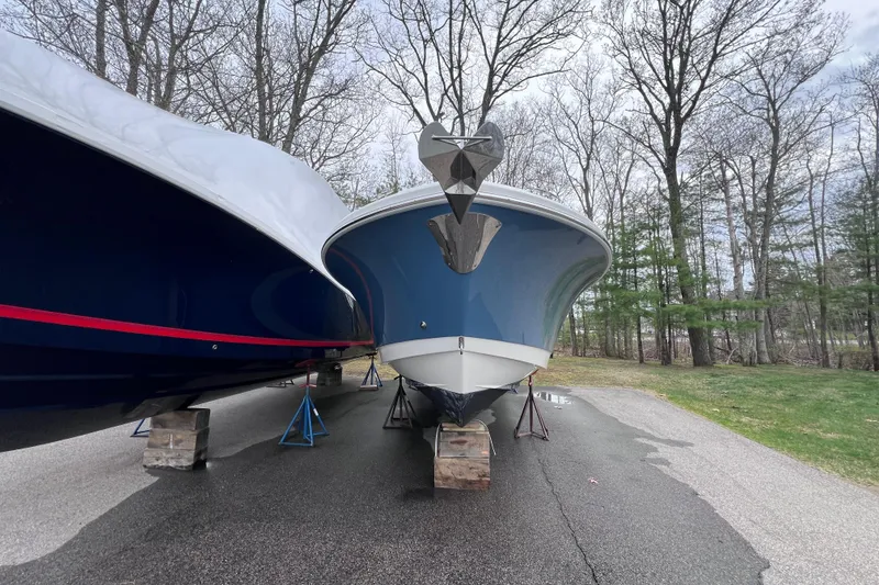 Slide: The Image of 2022 Edgewater 262CC boat on stands, surrounded by trees, parked on pavement. - 6
