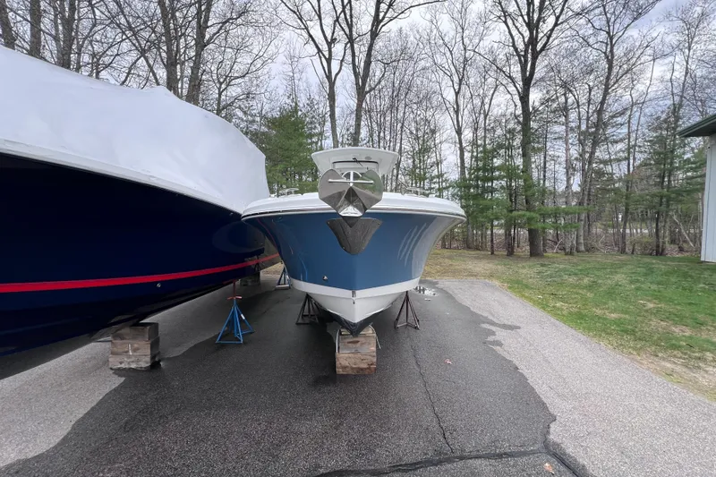 Slide: The Image of 2022 Edgewater 262CC boat on blocks, parked outdoors near trees. - 7