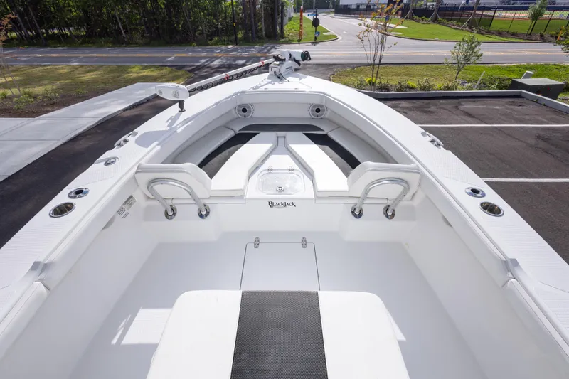 Slide: The Image of 2022 BlackJack 256 Coastal boat interior with seating and storage, parked near a road. - 21