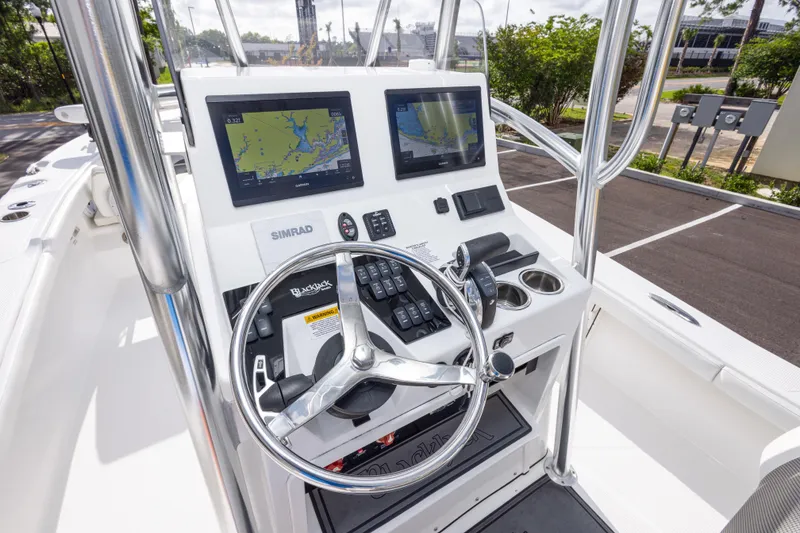 Slide: The Image of 2022 BlackJack 256 Coastal boat dashboard with navigation screens and steering wheel. - 22