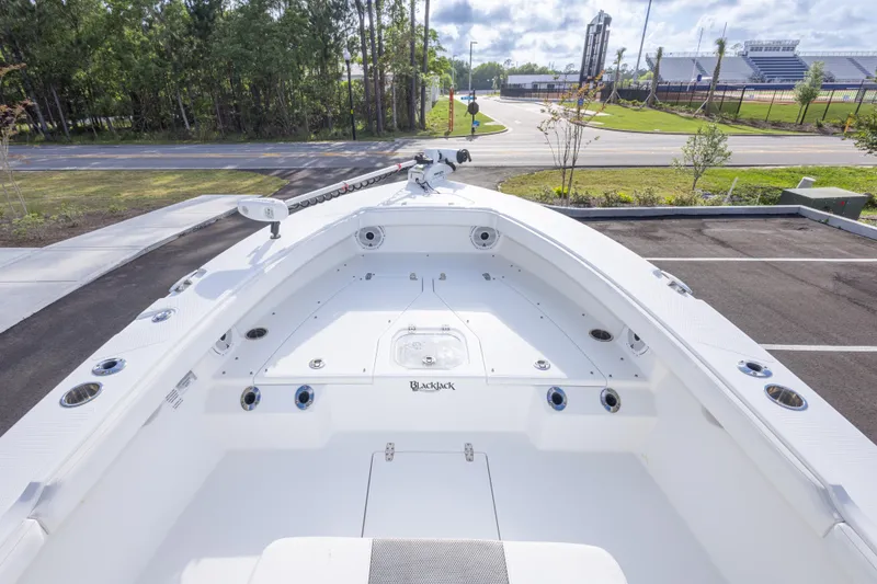 Slide: The Image of 2022 BlackJack 256 Coastal boat, spacious deck, parked near a road with trees and stadium. - 38