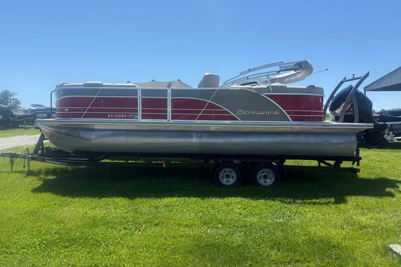 The Image of 2019 Berkshire 23RFX STS pontoon boat on trailer, red and silver design, parked on grass. - 1