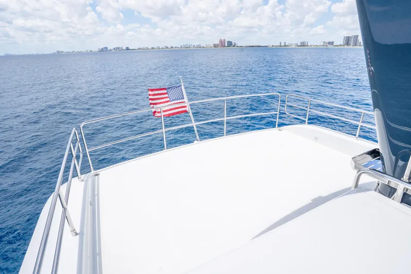 Slide: The Image of Sirena 58 yacht deck overlooking ocean, 2025 model, with city skyline in background. - 13