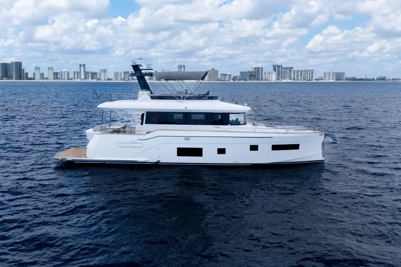 Slide: The Image of 2025 Sirena 58 yacht cruising on open water with city skyline in background. - 2
