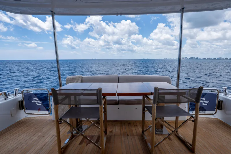 Slide: The Image of A luxurious Sirena 58 yacht deck with seating, overlooking the ocean under a partly cloudy sky. - 25