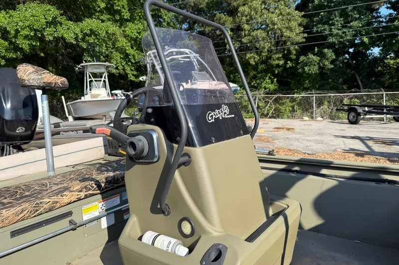 Slide: The Image of 2020 Tracker Grizzly 1860 CC Sportsman boat console with camouflage seating, outdoors. - 18