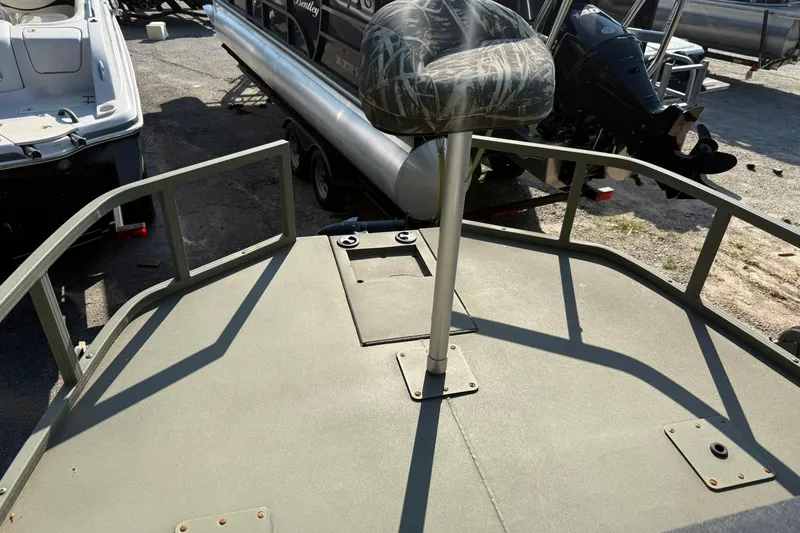 Slide: The Image of 2020 Tracker Grizzly 1860 CC Sportsman boat deck with camo seat, parked among other boats. - 5