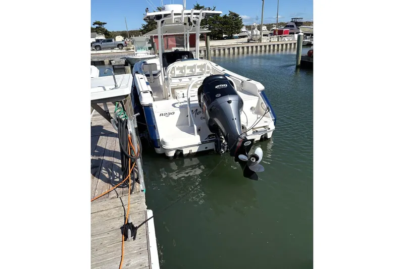 Slide: The Image of 2021 Robalo R230 Center Console boat docked in marina, rear view with outboard motor. - 4