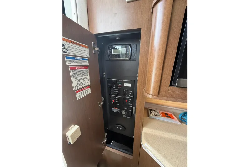 Slide: The Image of Electrical panel inside 2015 Sea Ray 280 Sunrunner boat, featuring control switches and warning labels. - 11