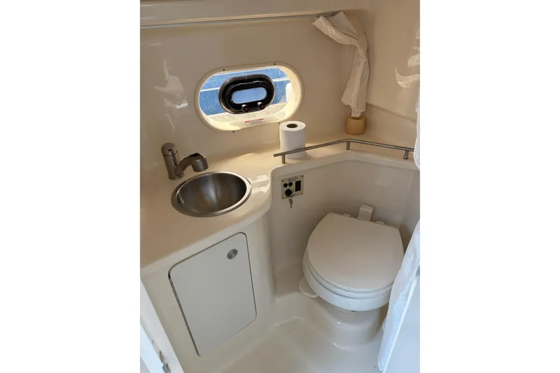 Slide: The Image of Compact bathroom in 2015 Sea Ray 280 Sunrunner boat with sink, toilet, and porthole window. - 14