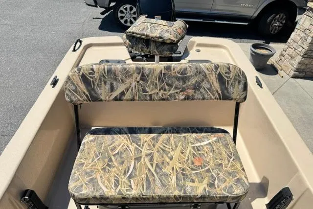 Slide: The Image of 2026 Carolina Skiff E18 JVX CC boat with camouflage seating, parked outdoors. - 9