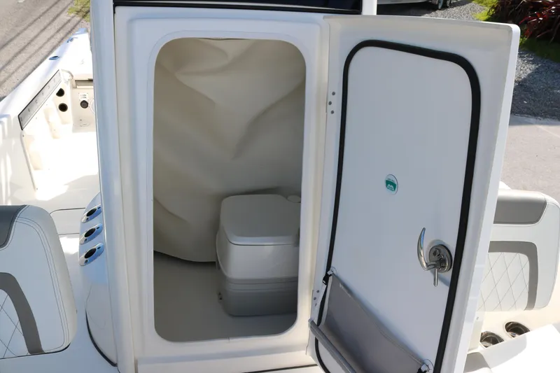 Slide: The Image of 2023 World Cat 235 CC boat interior with open door revealing compact toilet. - 15