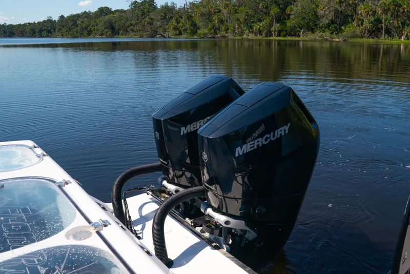 Slide: The Image of Twin Mercury engines on a 2025 Front Runner 43 Catamaran in a serene lake setting. - 68