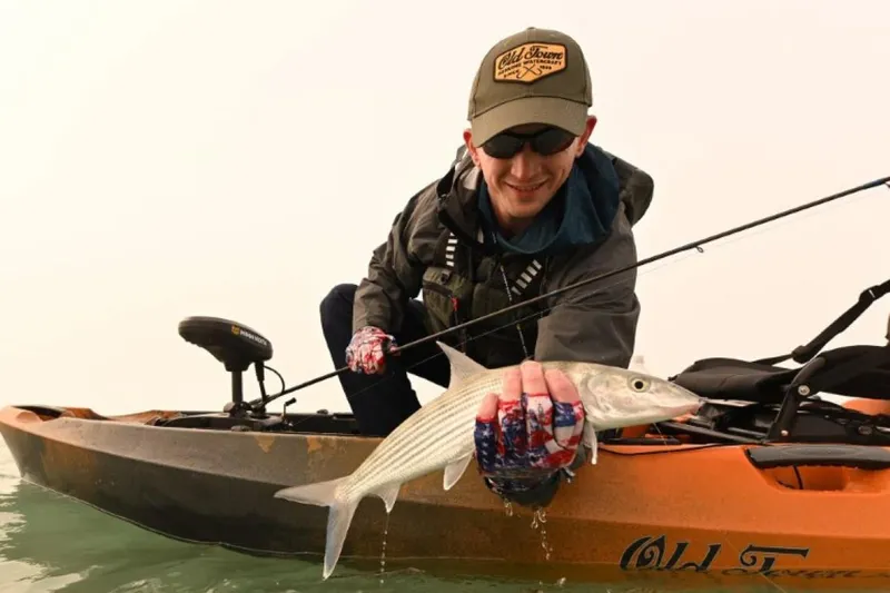 Slide: The Image of Man fishing from Old Town Sportsman Autopilot 120 kayak, holding a fish, 2023 model. - 1