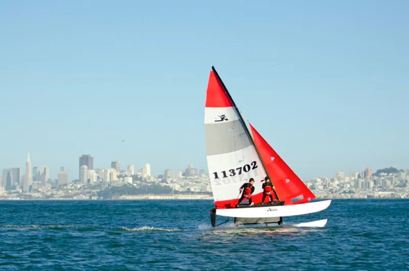 The Image of 2023 Hobie Cat H16 sailing near city skyline on a sunny day. - 0