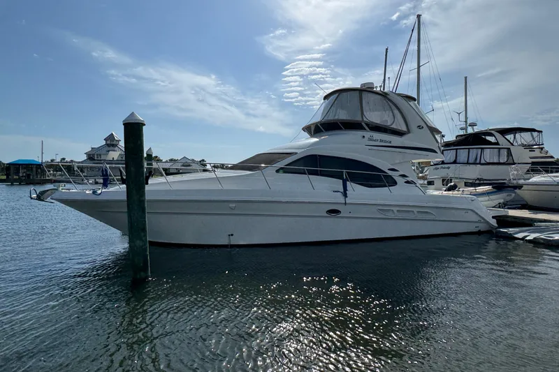 Slide: The Image of 2006 Sea Ray 44 Sedan Bridge yacht docked in a marina under a clear sky. - 2