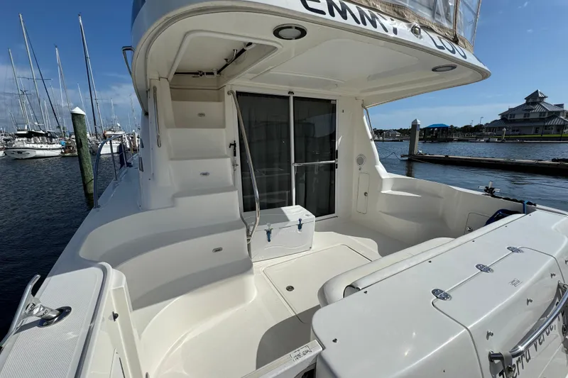 Slide: The Image of 2006 Sea Ray 44 Sedan Bridge yacht docked at marina, featuring spacious deck and seating area. - 7