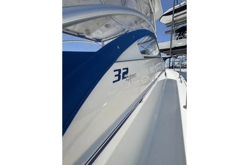 Slide: The Image of 2005 Pro-Line 32 Express boat with sleek blue and white design, docked under clear skies. - 15