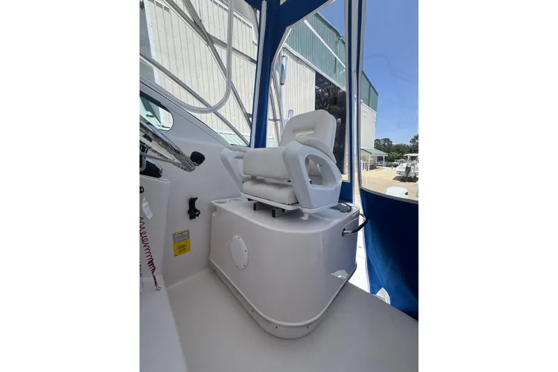 Slide: The Image of Captain's chair on 2005 Pro-Line 32 Express boat, featuring white upholstery and blue canopy. - 18