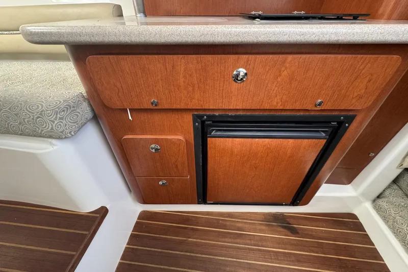 Slide: The Image of 2005 Pro-Line 32 Express boat interior with wooden cabinetry and compact refrigerator. - 26