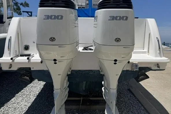 Slide: The Image of Twin 300 horsepower engines on a 2005 Pro-Line 32 Express boat, docked on gravel. - 6