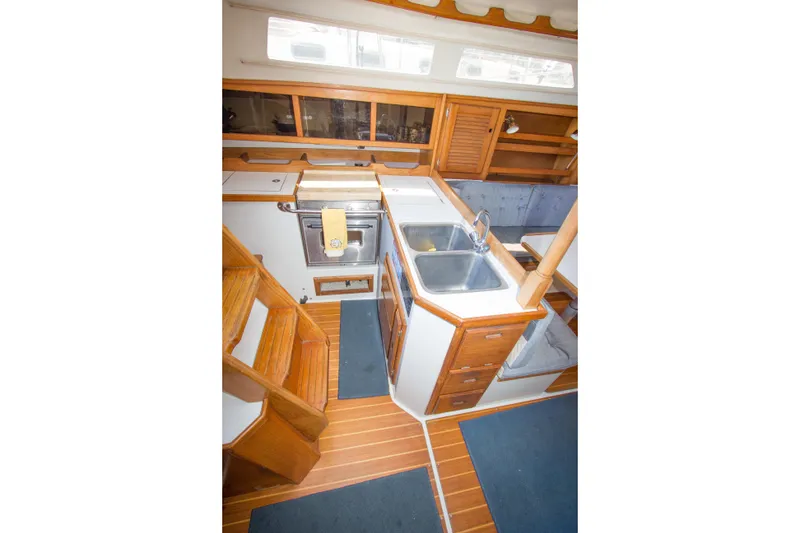 Slide: The Image of Interior of 1991 Catalina 36 sailboat featuring a compact kitchen with wooden cabinetry. - 13