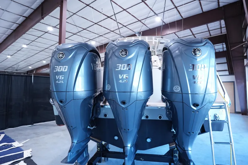 Slide: The Image of 2023 Grady-White Canyon 336 with triple Yamaha 300 V6 outboard engines in a warehouse. - 1