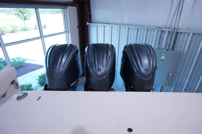 Slide: The Image of 2023 Grady-White Canyon 336 boat with triple outboard engines in a showroom. - 2